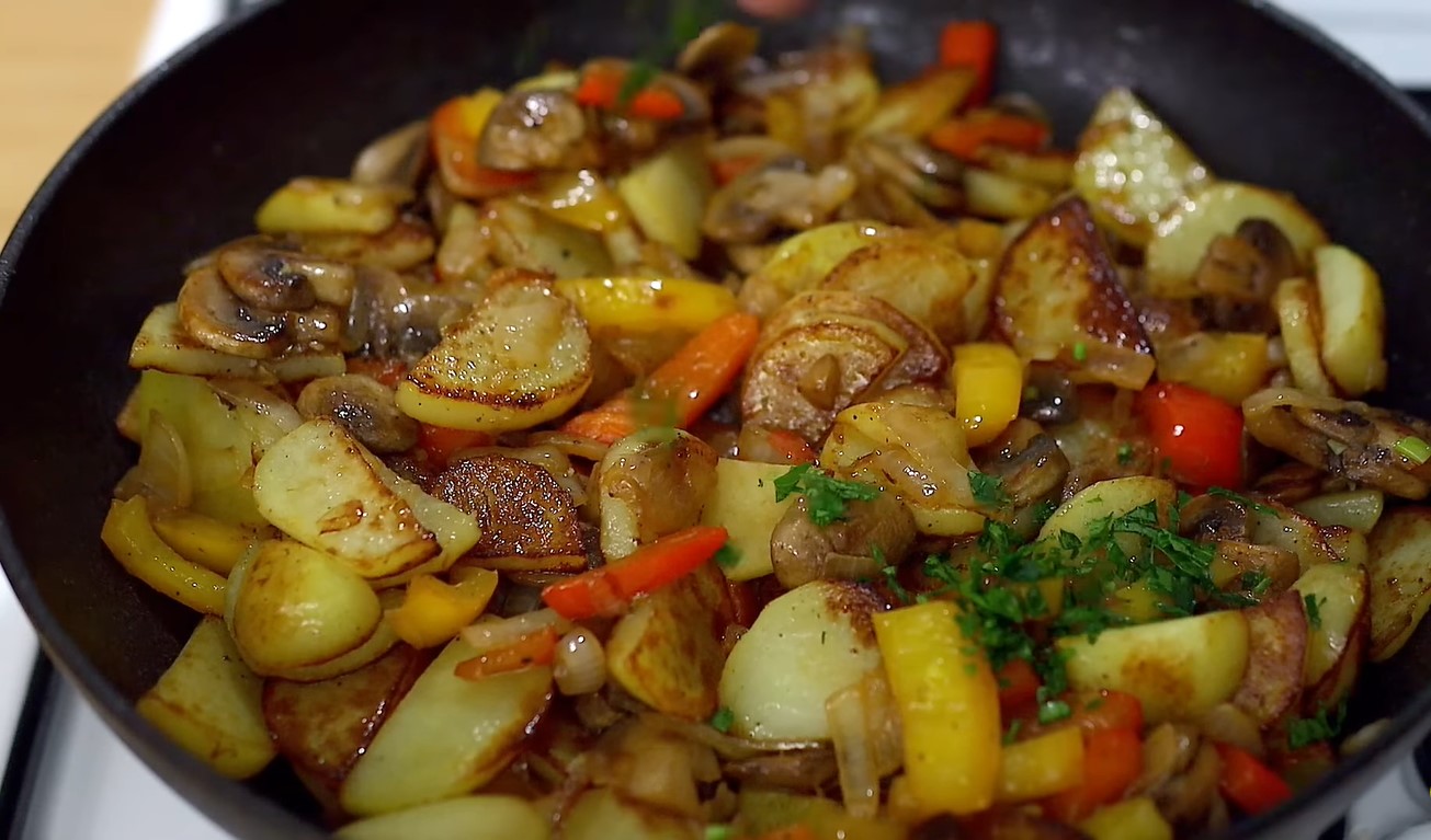 Knusprige Bratkartoffeln mit Champignons und Paprika in einer Pfanne ...